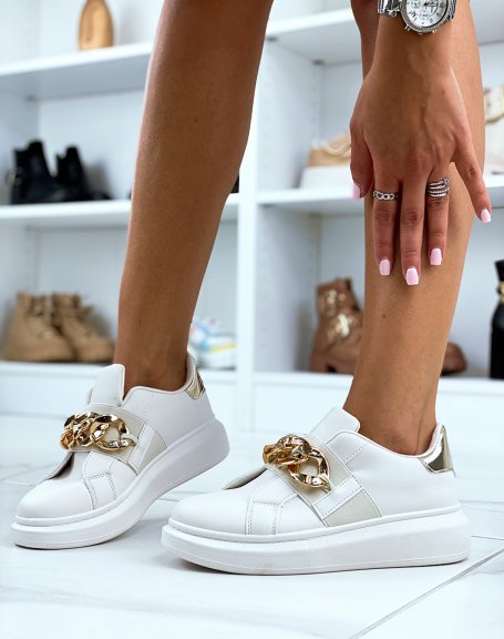 Beige sneakers adorned with a golden chain