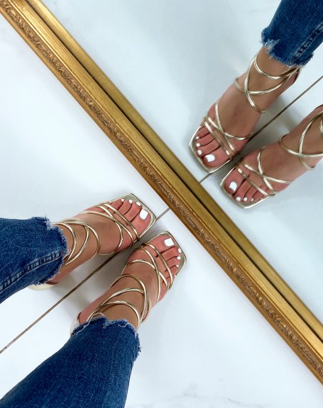 Golden sandals with intersecting straps and rounded heel