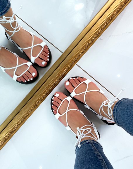 White flat sandals with long straps and notched sole