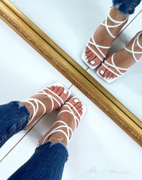 White sandals with intersecting straps and rounded heel